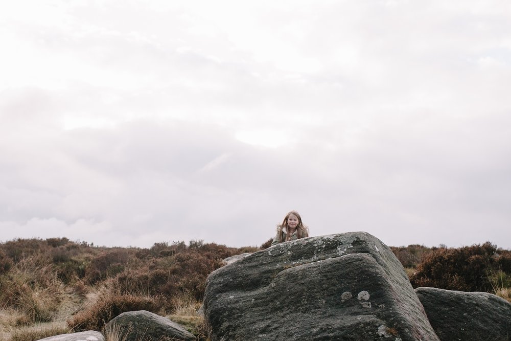 little girl hiding behind a rock