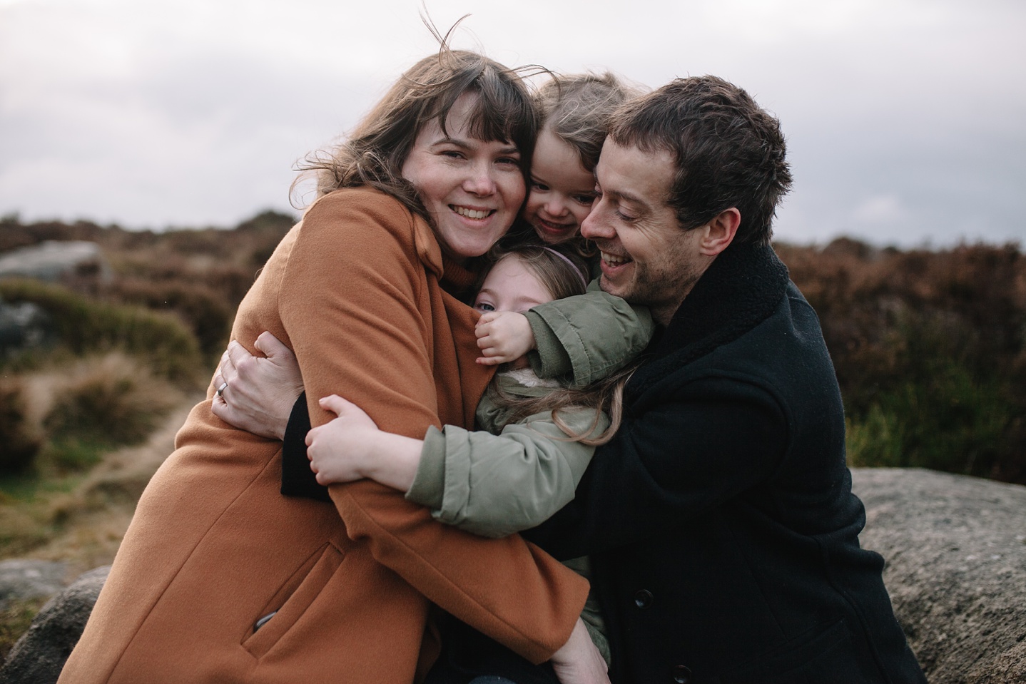 mum, dad and two little girls having a big hug and laughing