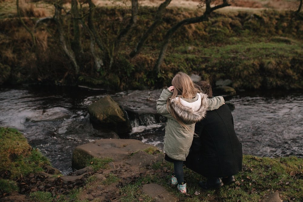 dad crouched down with little girl looking at the river