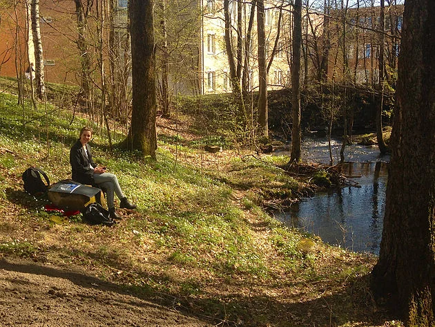 En mosekledd sittestein med perfekt utsikt til bekken og (etter hvert) til hytta. Vida tester ut sittekomforten.