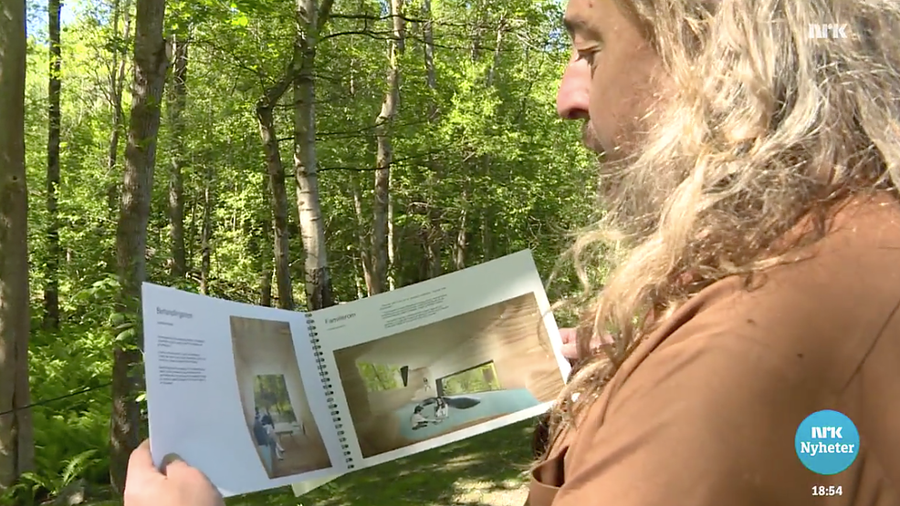 Håvard viser planene for hytta i naturomgivelsene. 