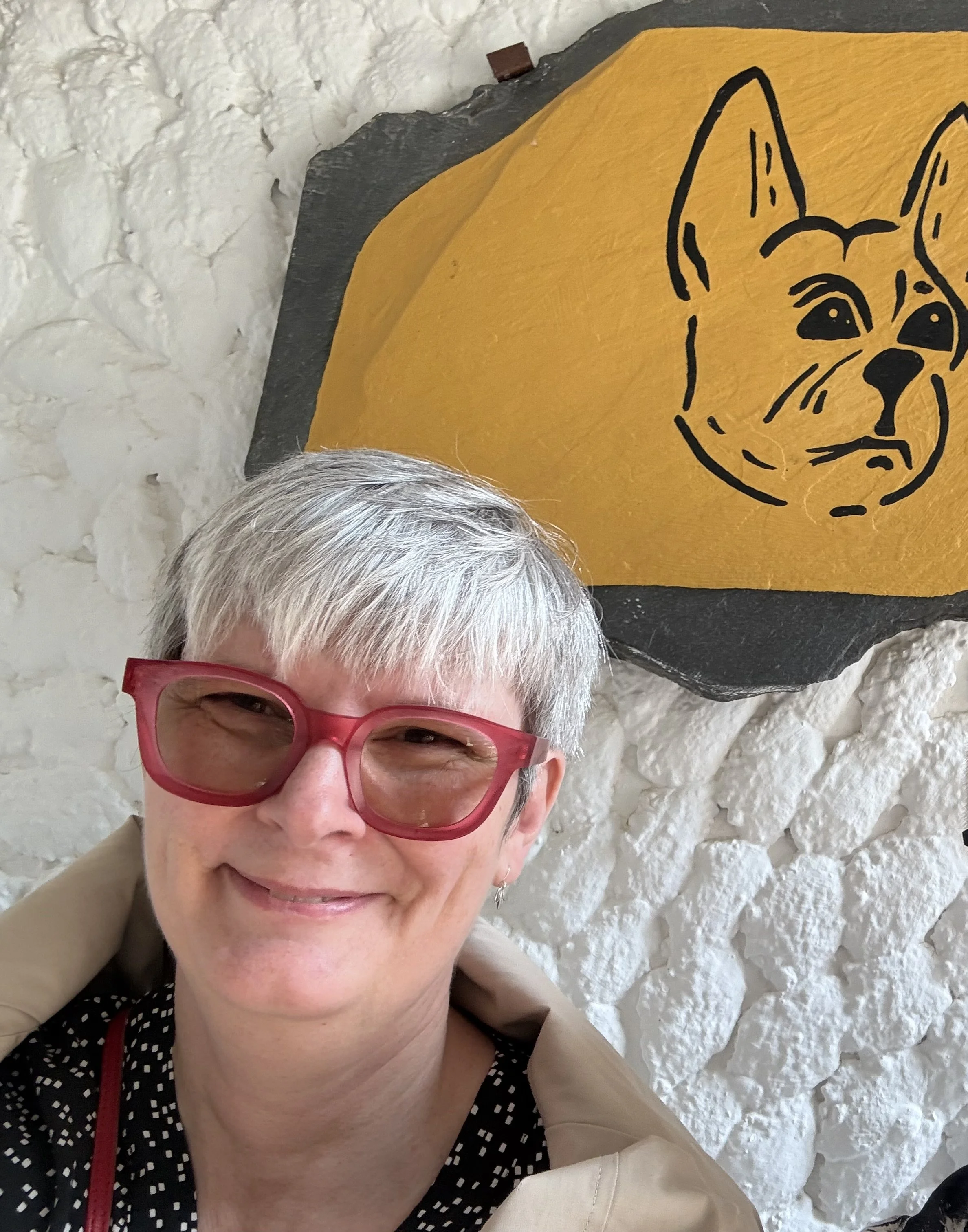 person smiling while seated in front of a sign with a bulldog on it