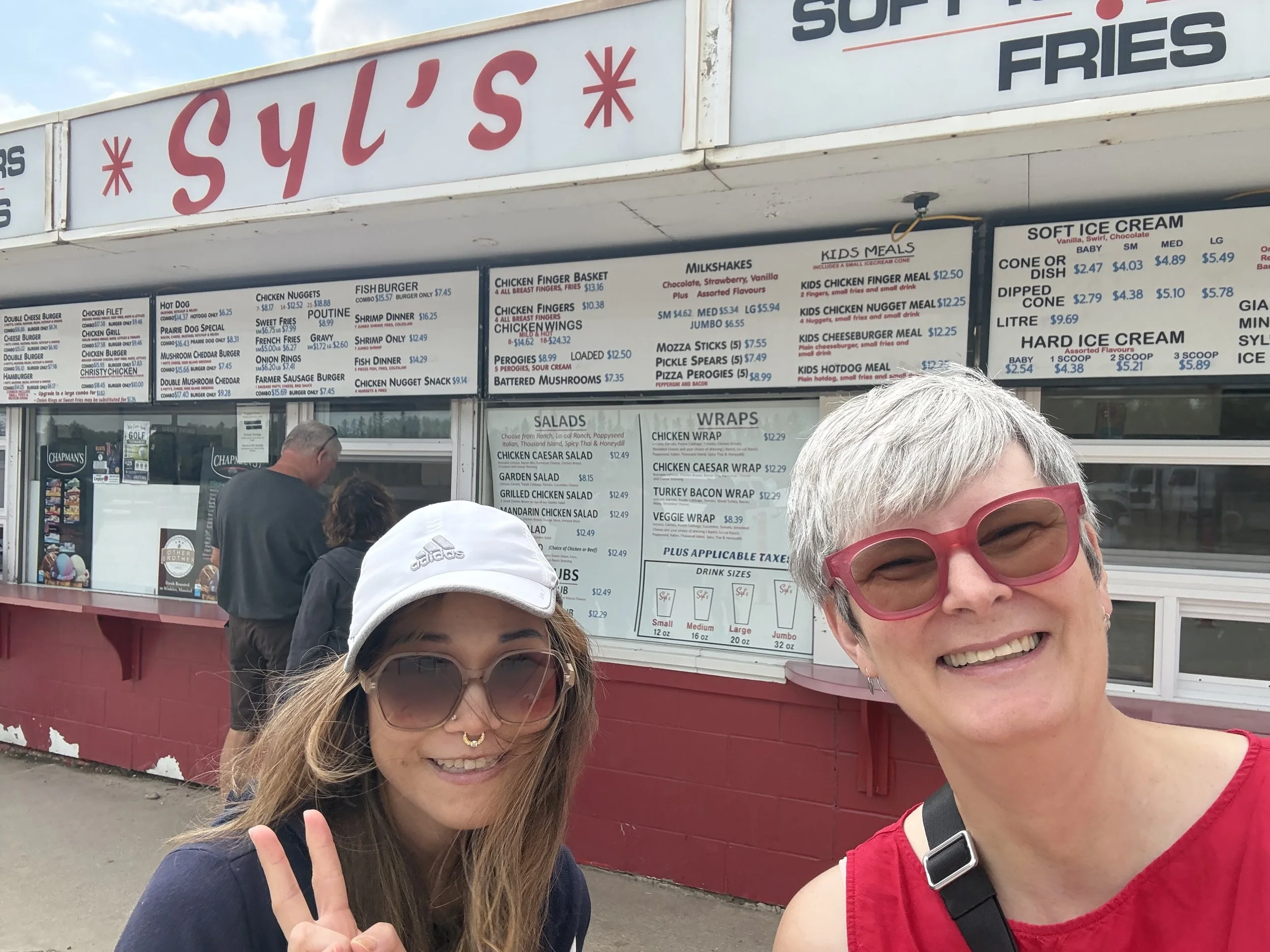 Two smiling people pose in front of a burger stand.