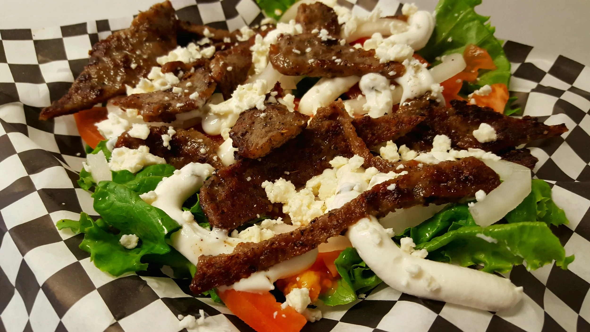 GREEK SALAD: A bed of crisp lettuce, tomatoes, onions topped with gyro meat ( lamb and beef ) and feta cheese.