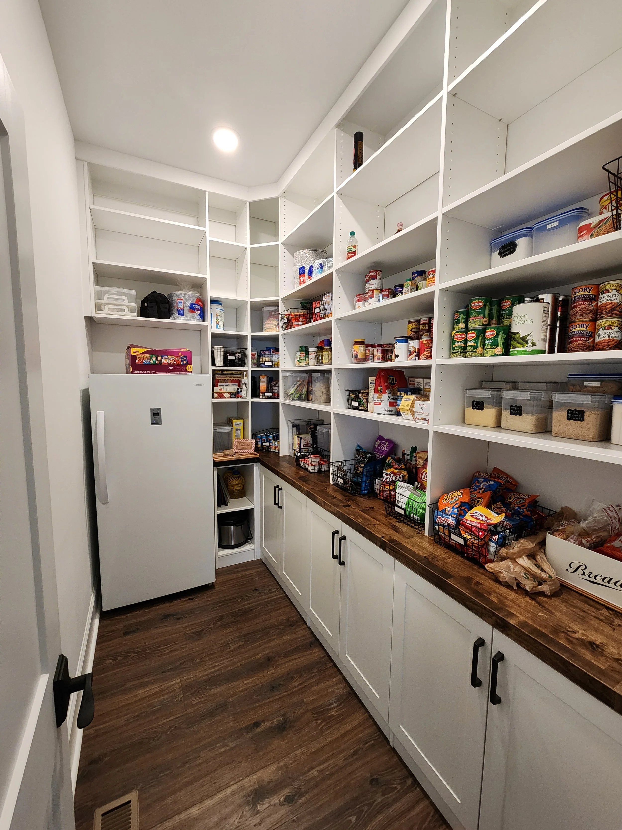 Custom pantry with floor-to-ceiling shelving, butcher block countertops, and white shaker cabinets installed by NC Visionz.