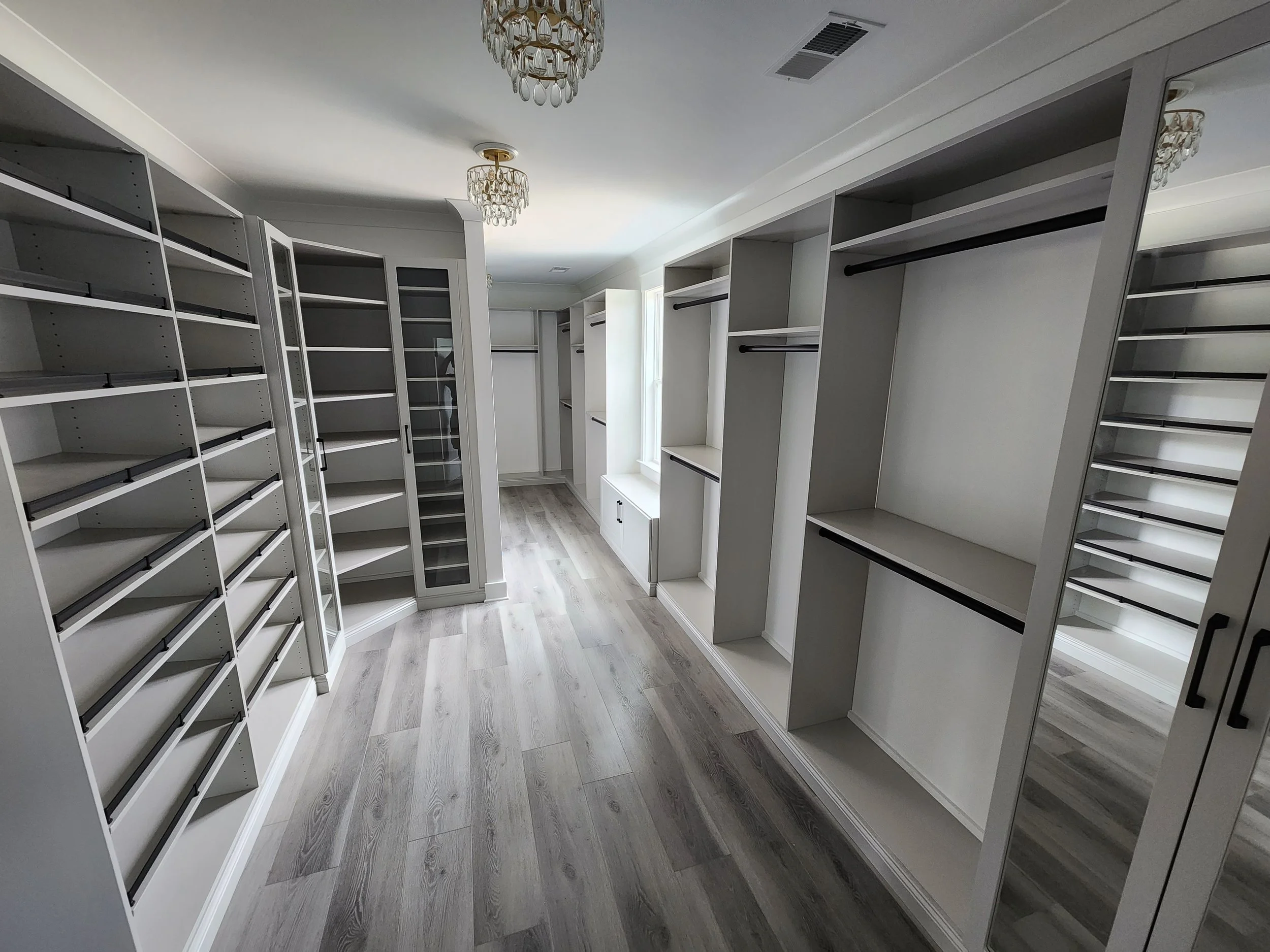 Custom master walk-in closet built-in drawers,  countertops,and glass-front cabinets designed and installed by NC Visionz in Denver, NC.