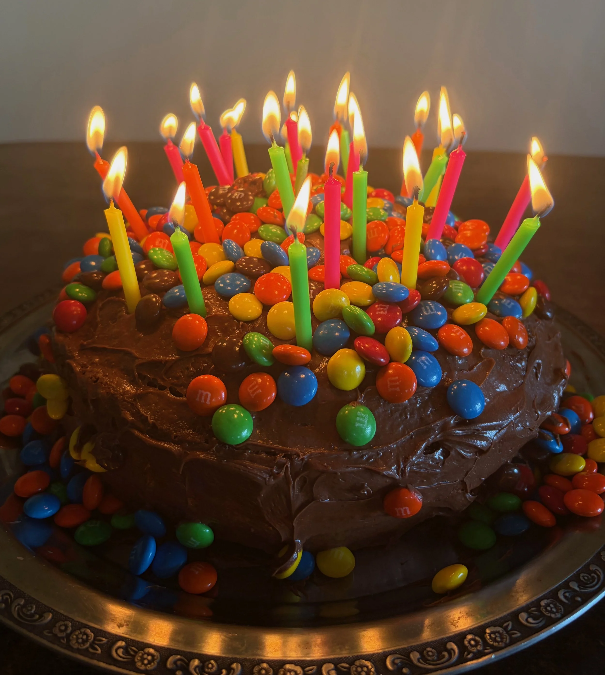 M&M covered chocolate cake with lit birthday candles