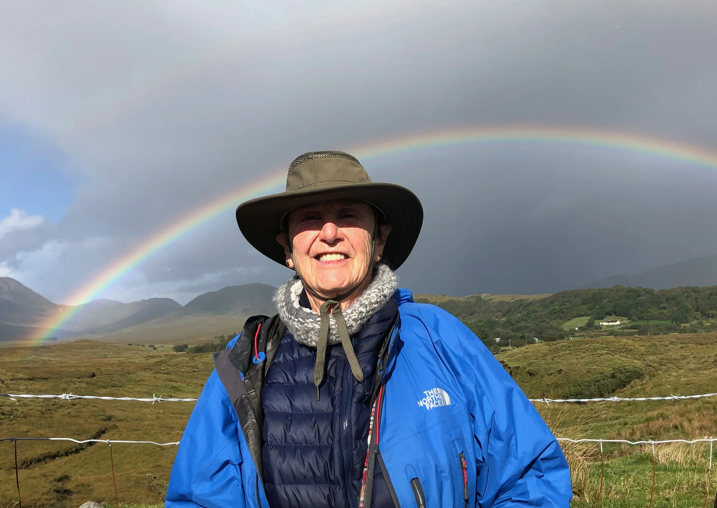 Sheila Kogan Author in Ireland under a double rainbow in green hills