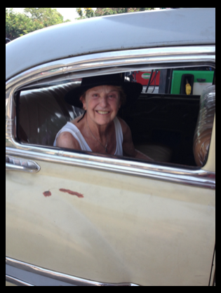 Sheila peeking out the window of the back seat of a classic 1950s car