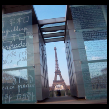 Eiffel Tower in Paris seen next to glass walls of the word Peace in every language