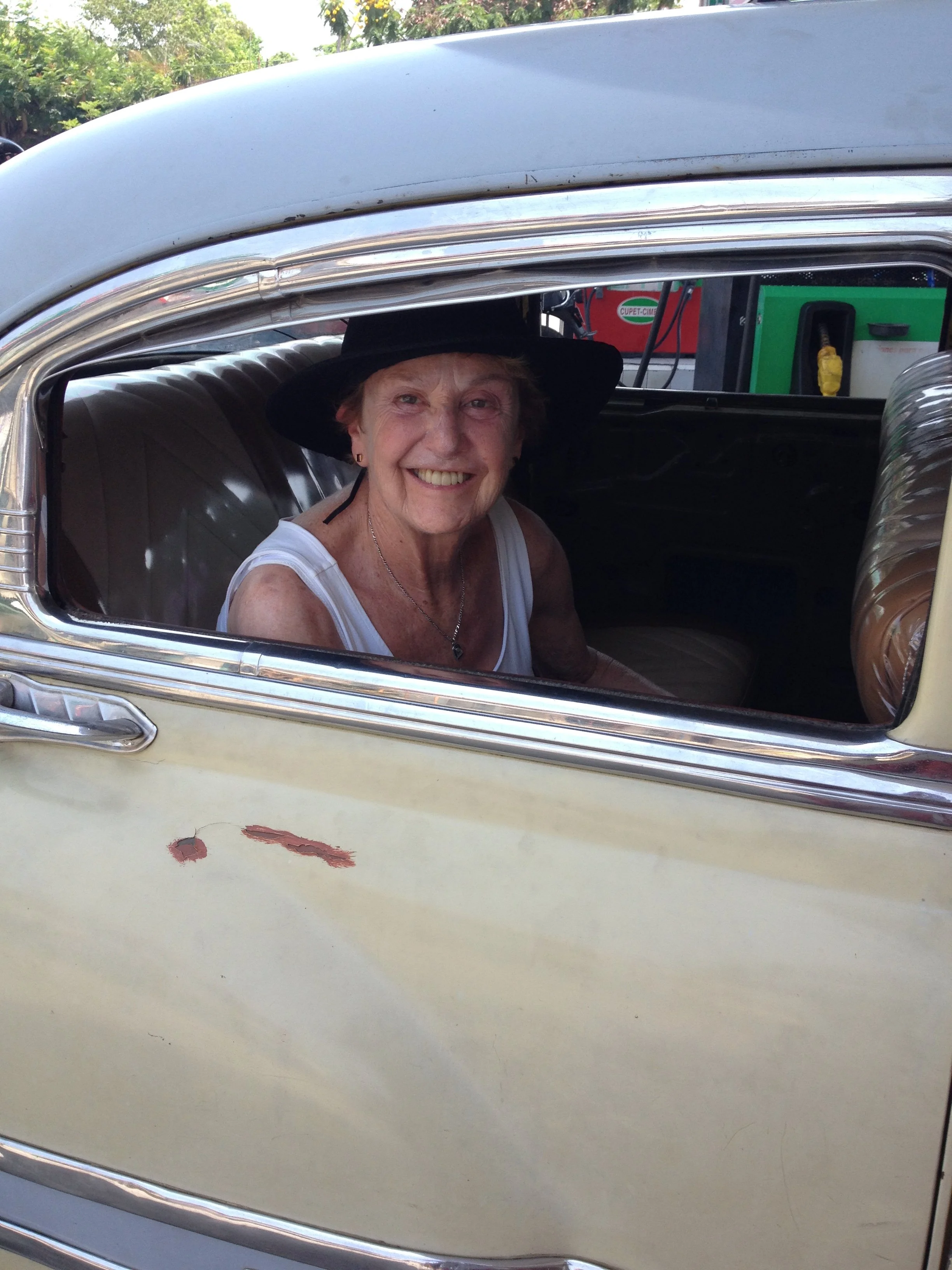 Sheila peeking out the window of the back seat of a classic 1950s car