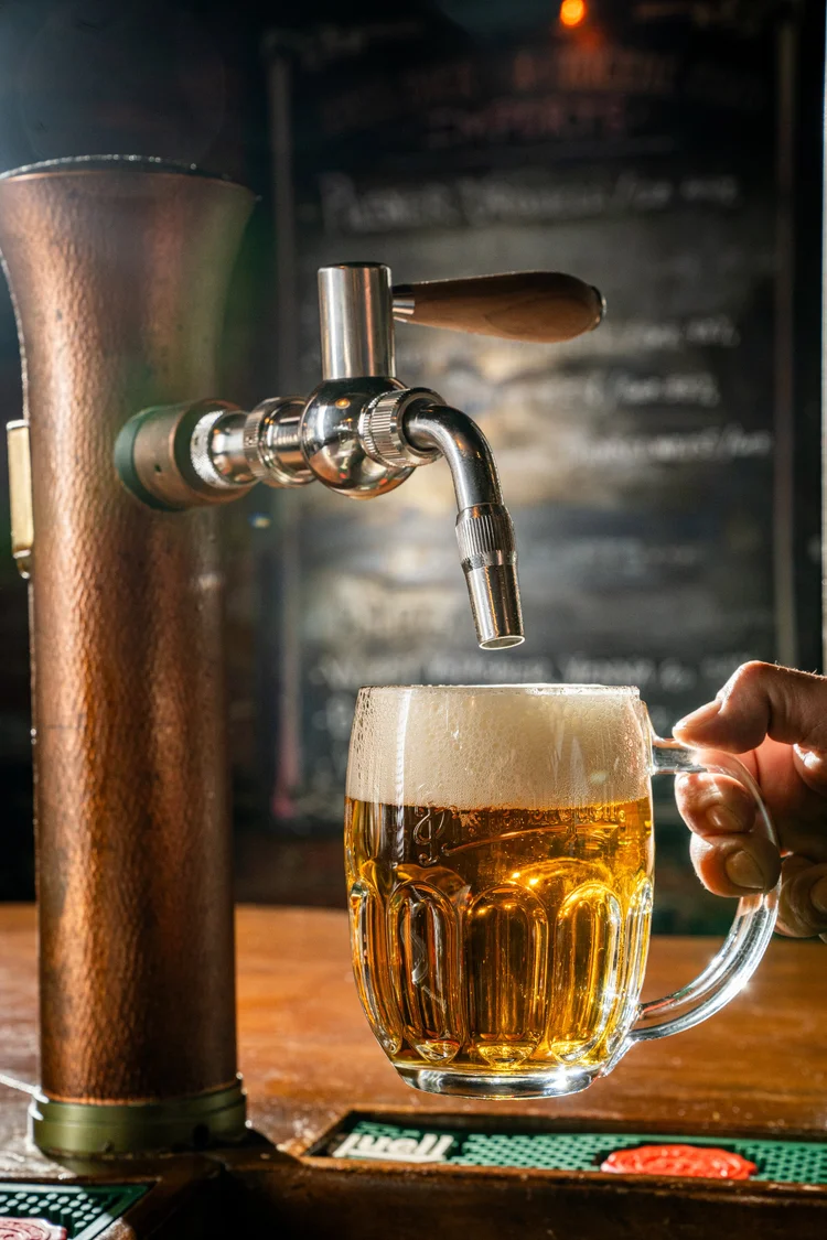 Chopp dourado sendo servido em uma caneca, com espuma cremosa