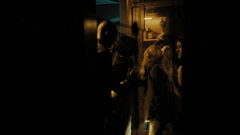 Group of people engaging in conversation in a dimly lit room with warm lighting.
