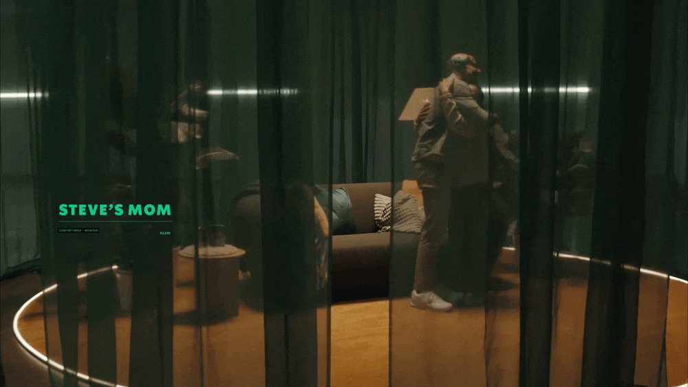 A reflection of two women at a nightclub or lounge, with black curtains and seating visible, and a caption reading 'Steve's Mom' on the screen.