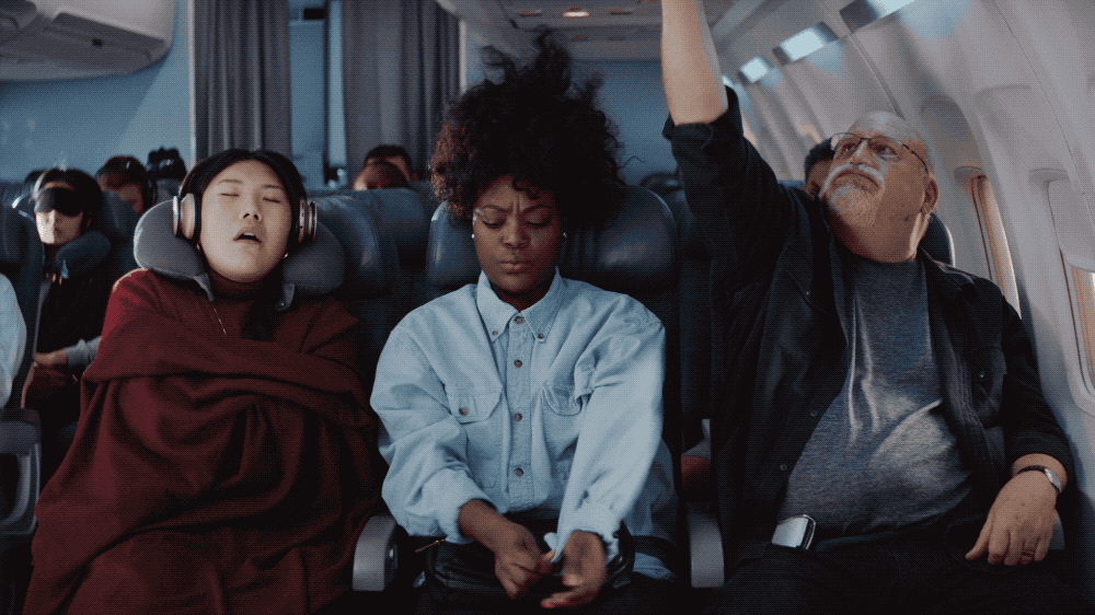 People sleeping and resting on an airplane, with one person waking up.