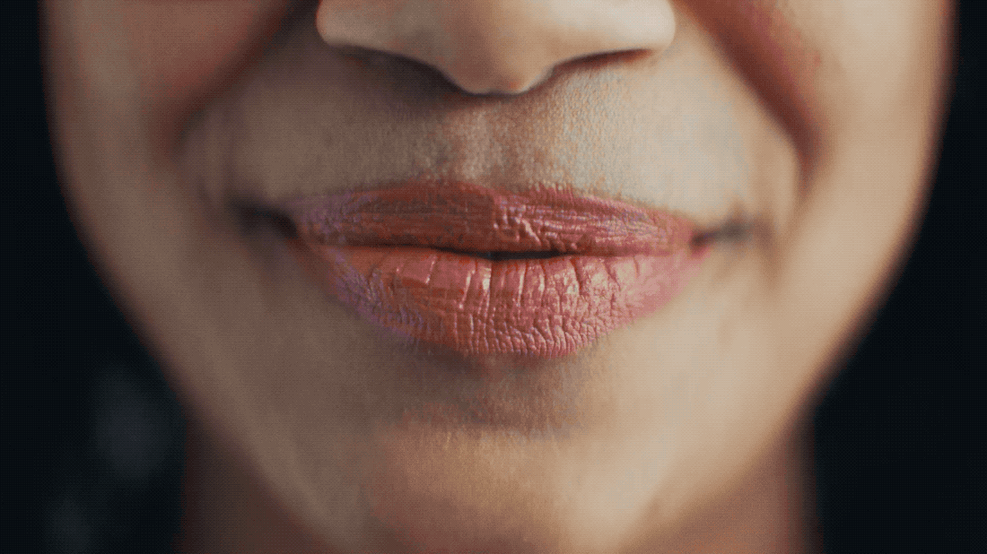 Close-up of a person's lips with pink lipstick, showing texture and cracks