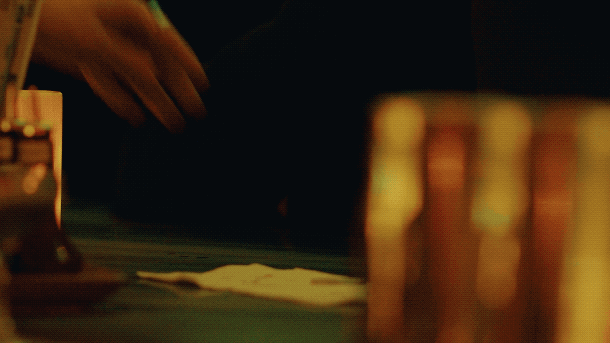 A hand reaching towards a stack of poker chips on a green felt poker table.