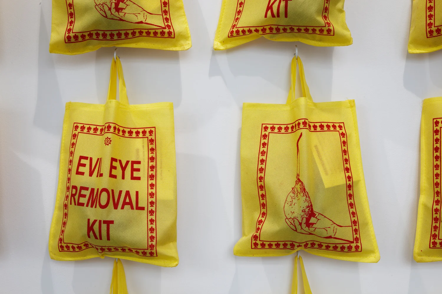 “Evil Eye Removal Kits” Camphor, turmeric, letterpress instruction card and coconut in custom tote bag, installation view, Nature Morte, Berlin, 2013