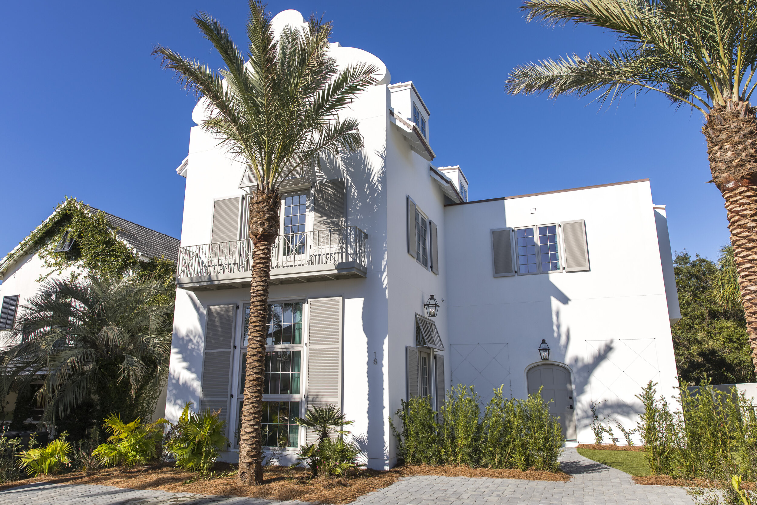 White two-story house with palm trees