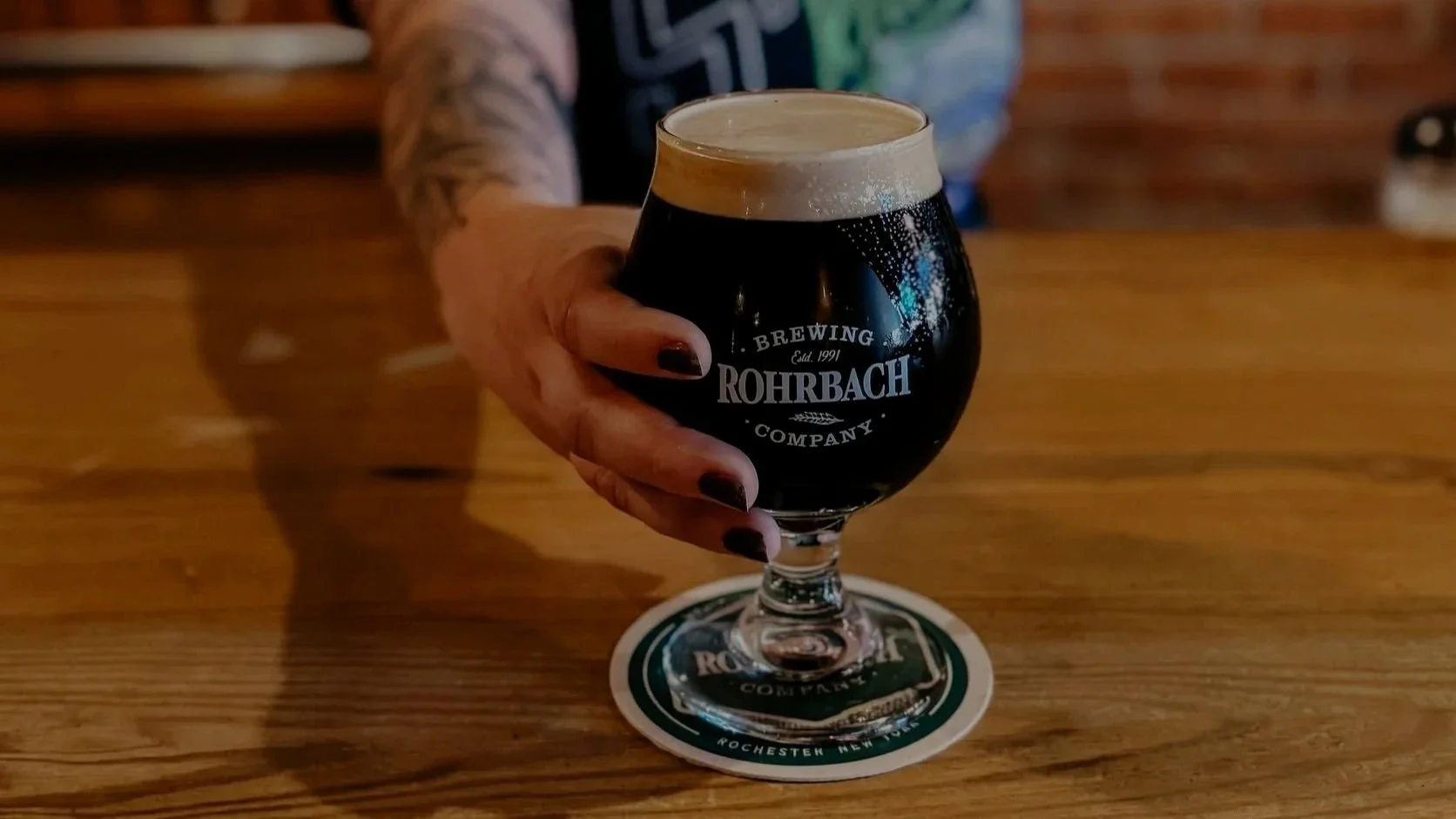 A Rohrbach bartender serves a glass of dark beer with a creamy foam head across the wooden bar.A Rohrbach bartender serves a glass of dark beer with a creamy foam head across the wooden bar.