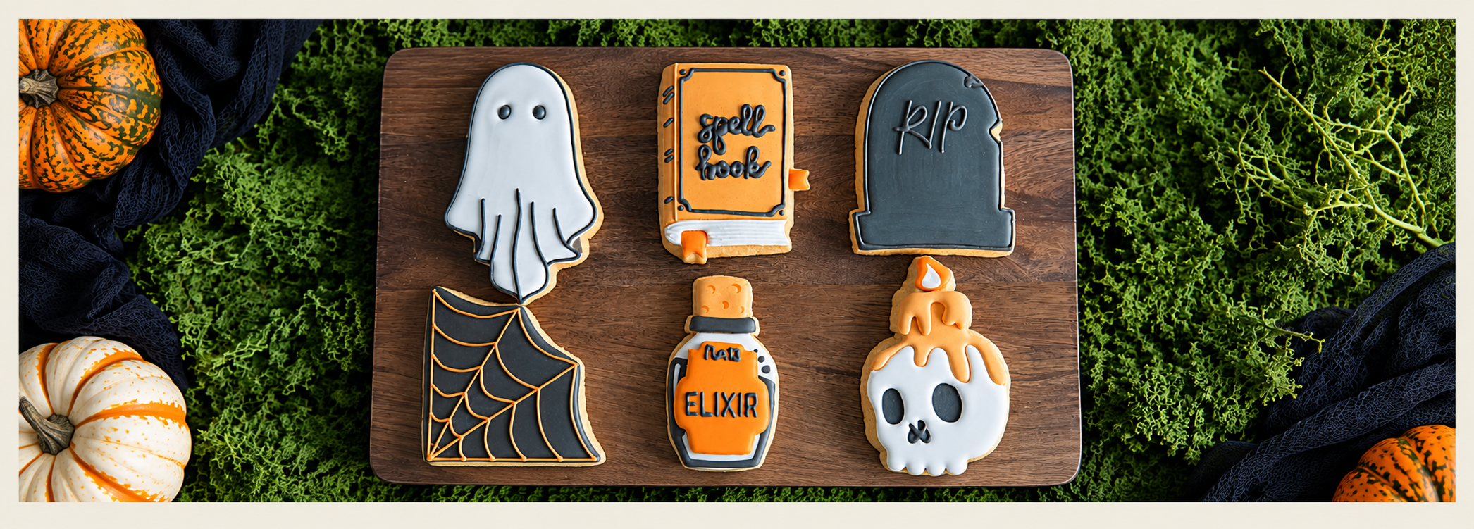 Six Halloween sugar cookies decorated as a ghost, spell book, tombstone, spiderweb, potion, and skull.