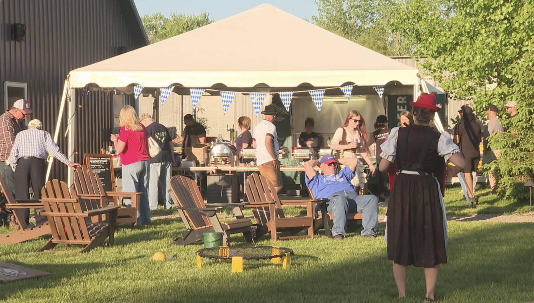 Guests gathering outside under a tent at Rohrbach’s Frühlingsfest with lawn games and evening sunshine.