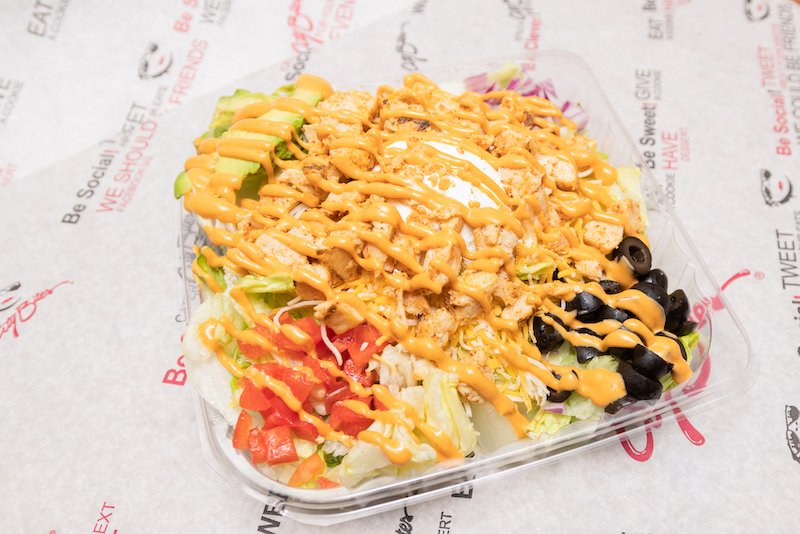   Baja Chicken Salad   Fritos® corn chips, grilled chicken, shredded lettuce, tomatoes, red onions, black olives, shredded cheddar, topped with sour cream, sliced avocado, and chipotle sauce. 