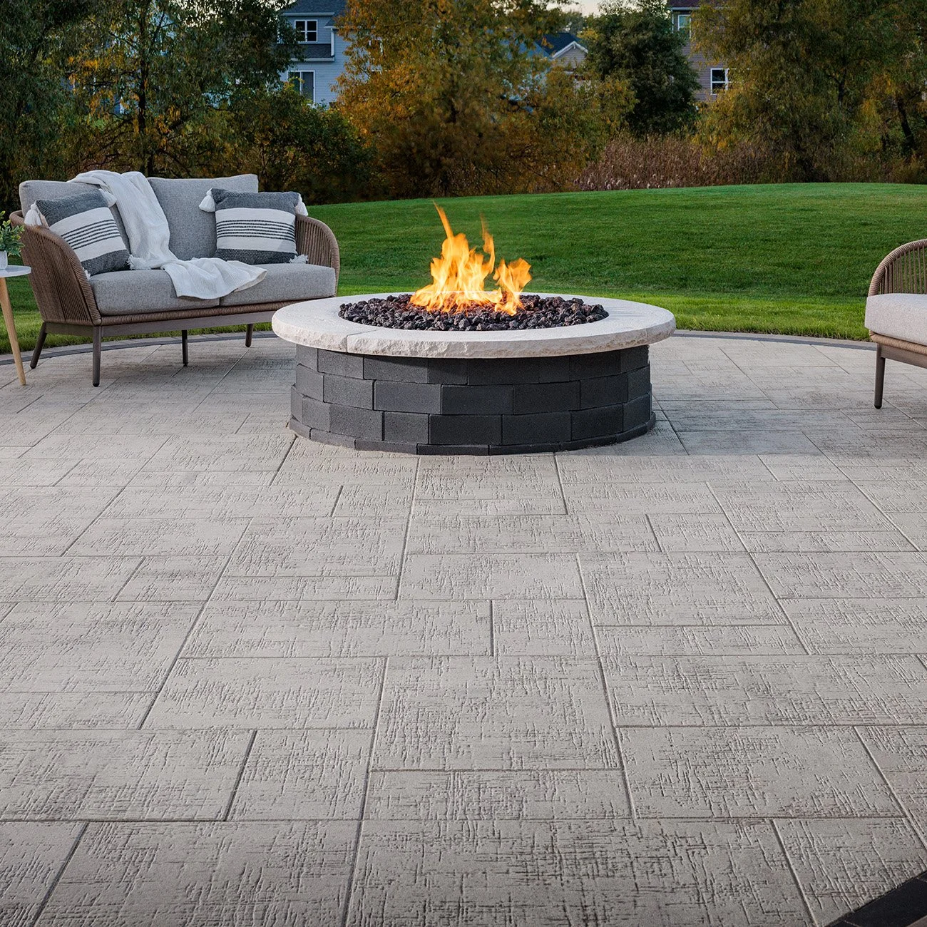 A round Melville fire pit is the centerpiece of a backyard patio.