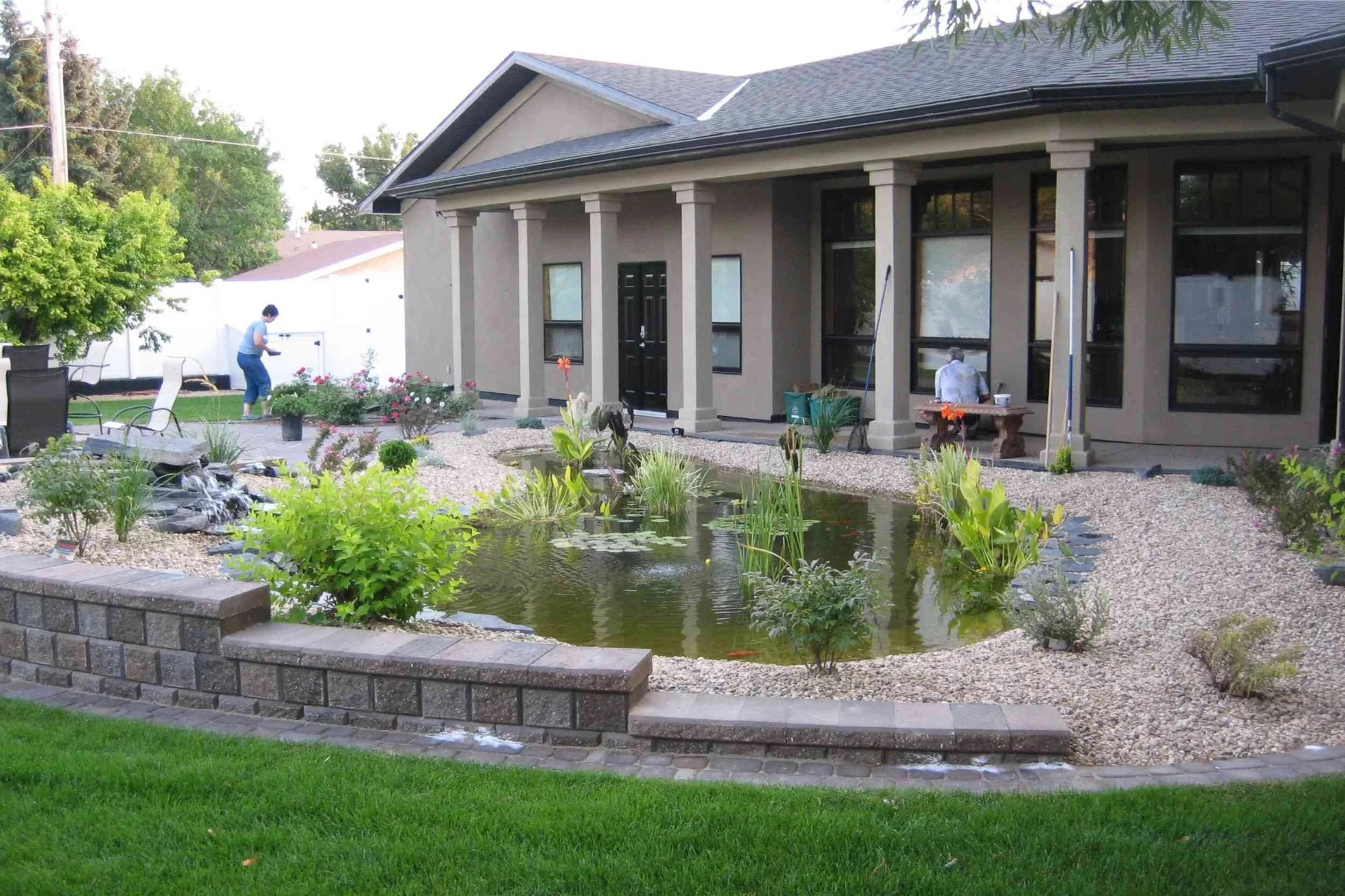 A variable height garden wall separates the pond and patio from the lawn