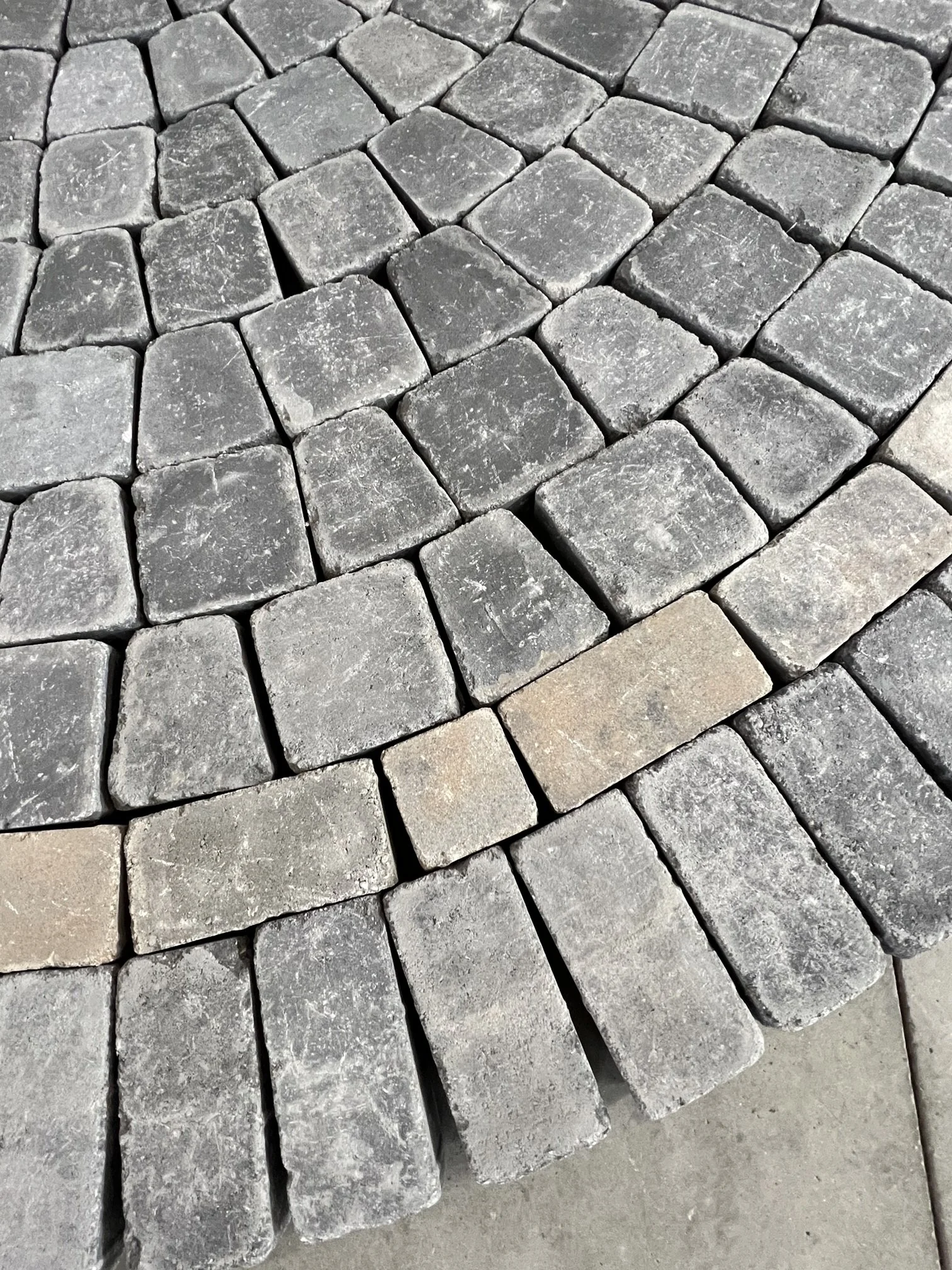 Close-up of grey and taupe patio stones. The stones are in cocentric circles, creating a circular patio.