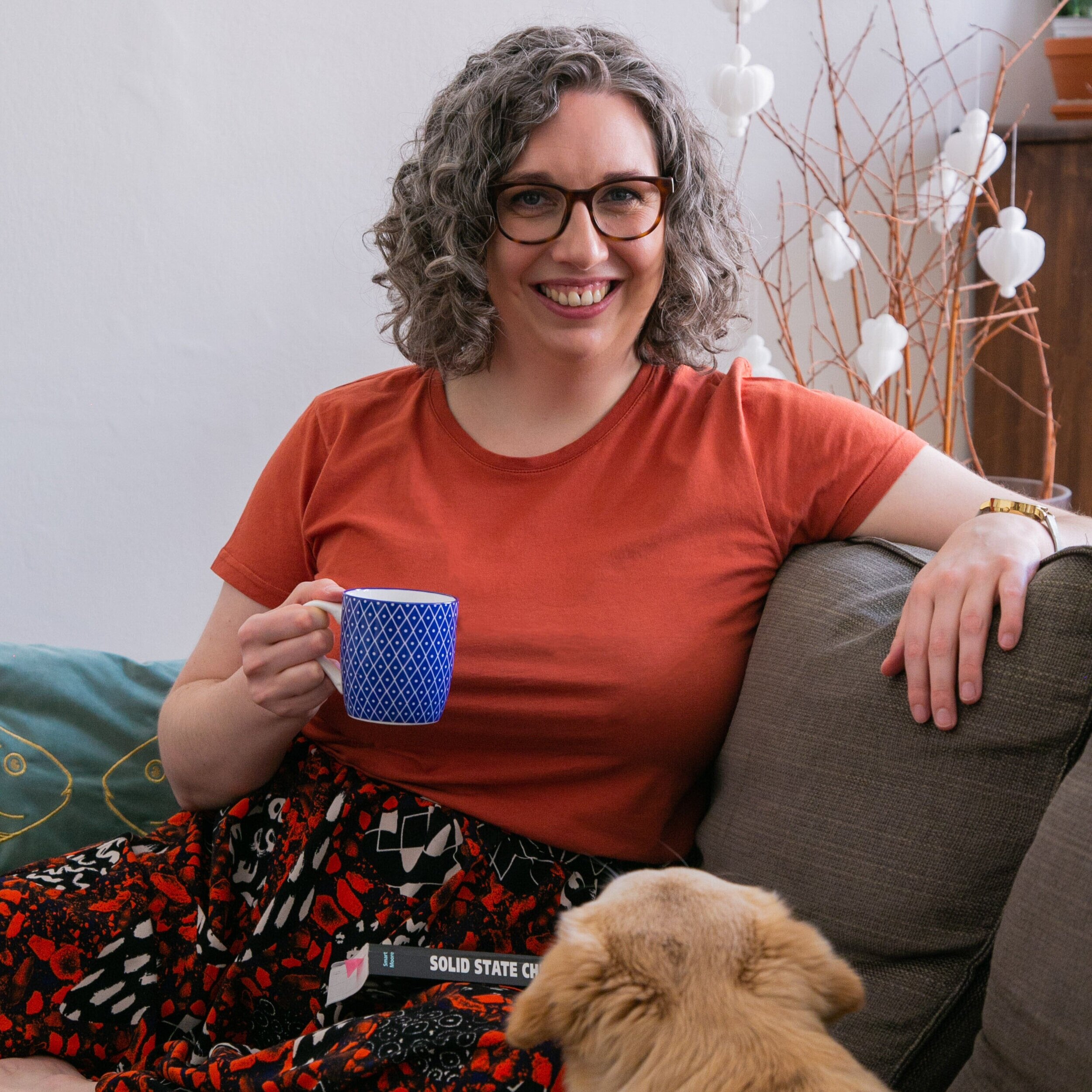 Photo of Academic Writing Coach Dr Anna Clemens relaxing on the sofa with her dog Zuza