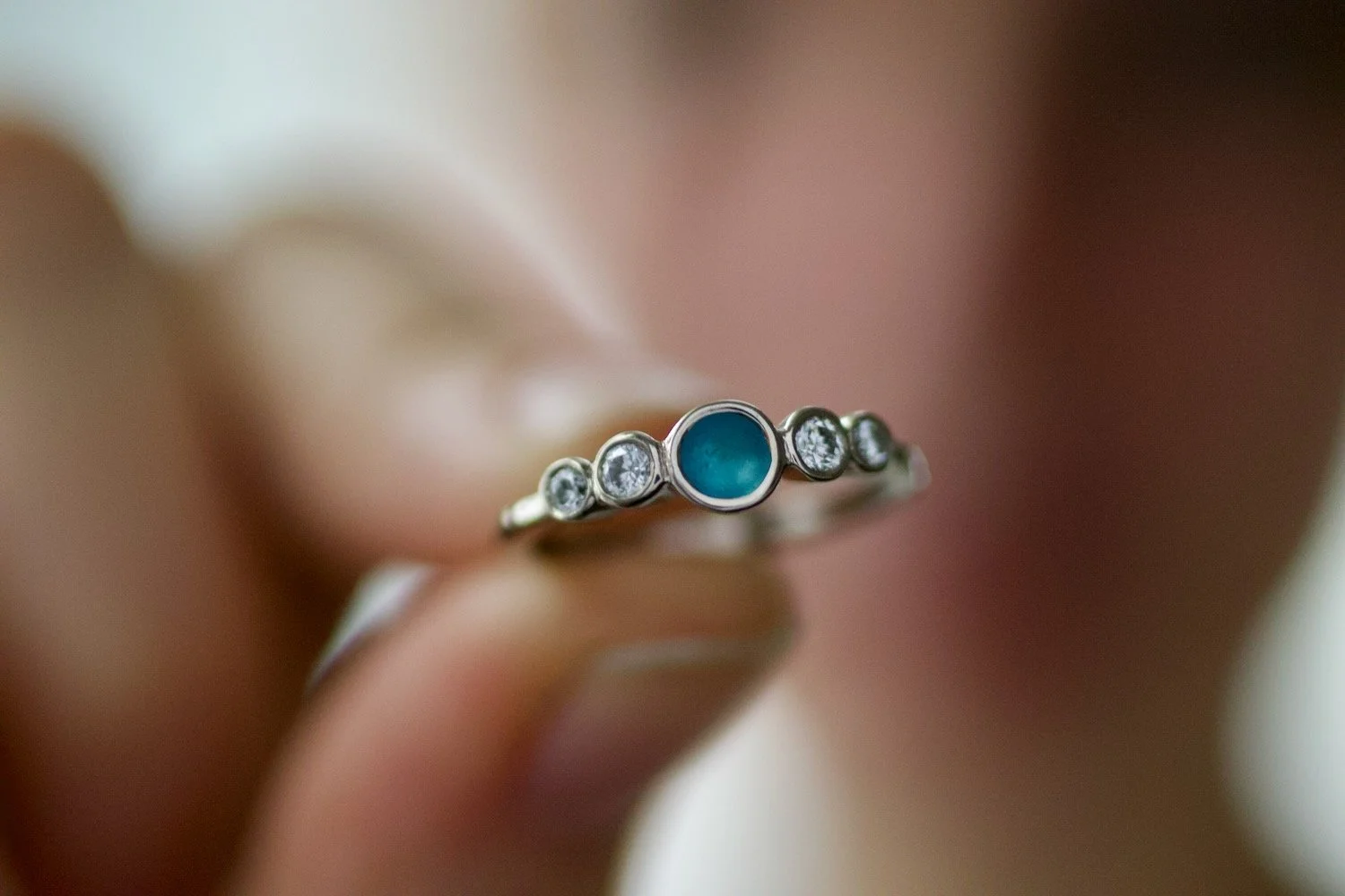 Garlana Sea Glass and Diamond Engagement Ring being held between two fingers