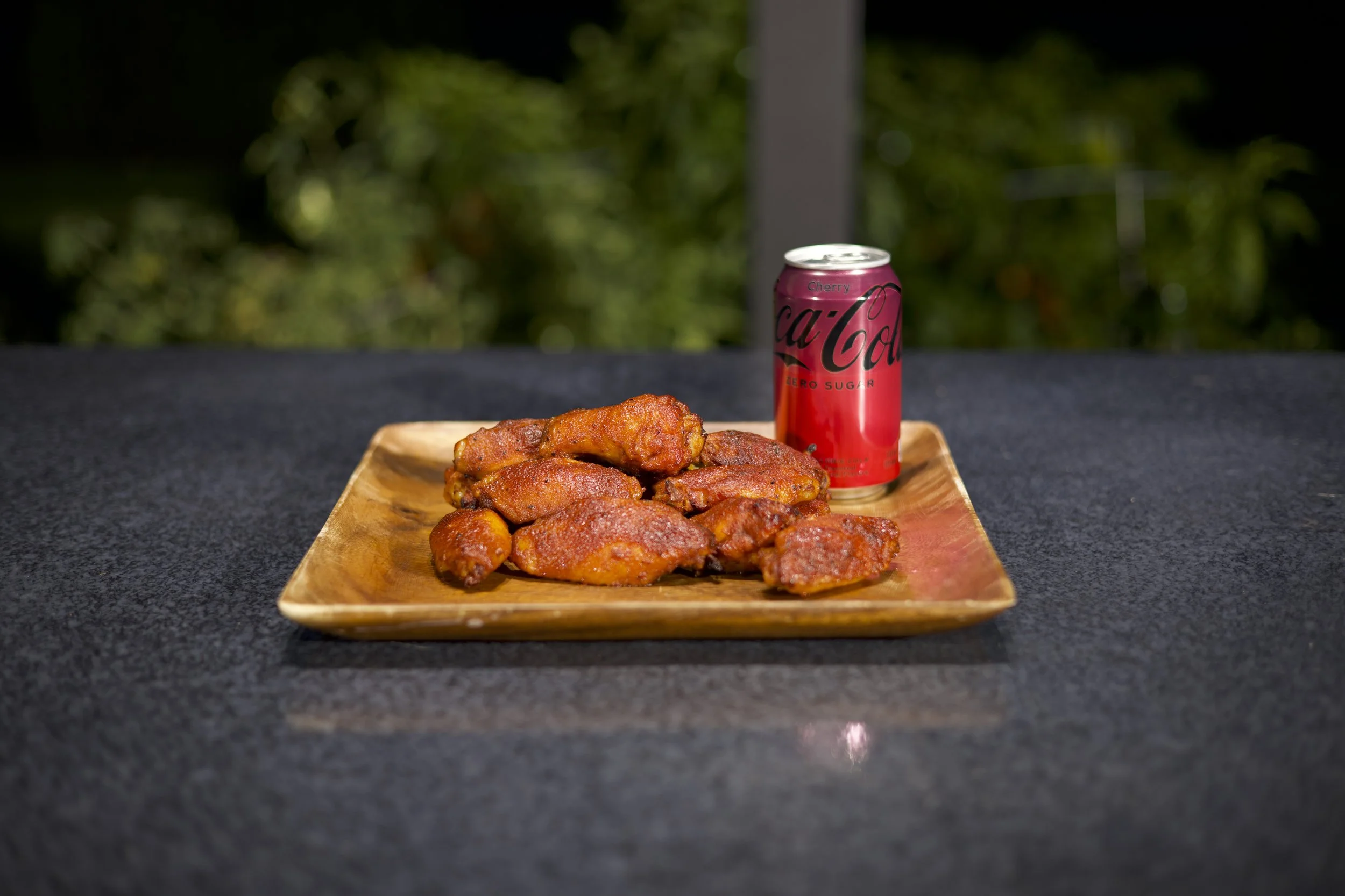 Plate of smoked Cherry Coke chicken wings next to a can of Cherry Coke