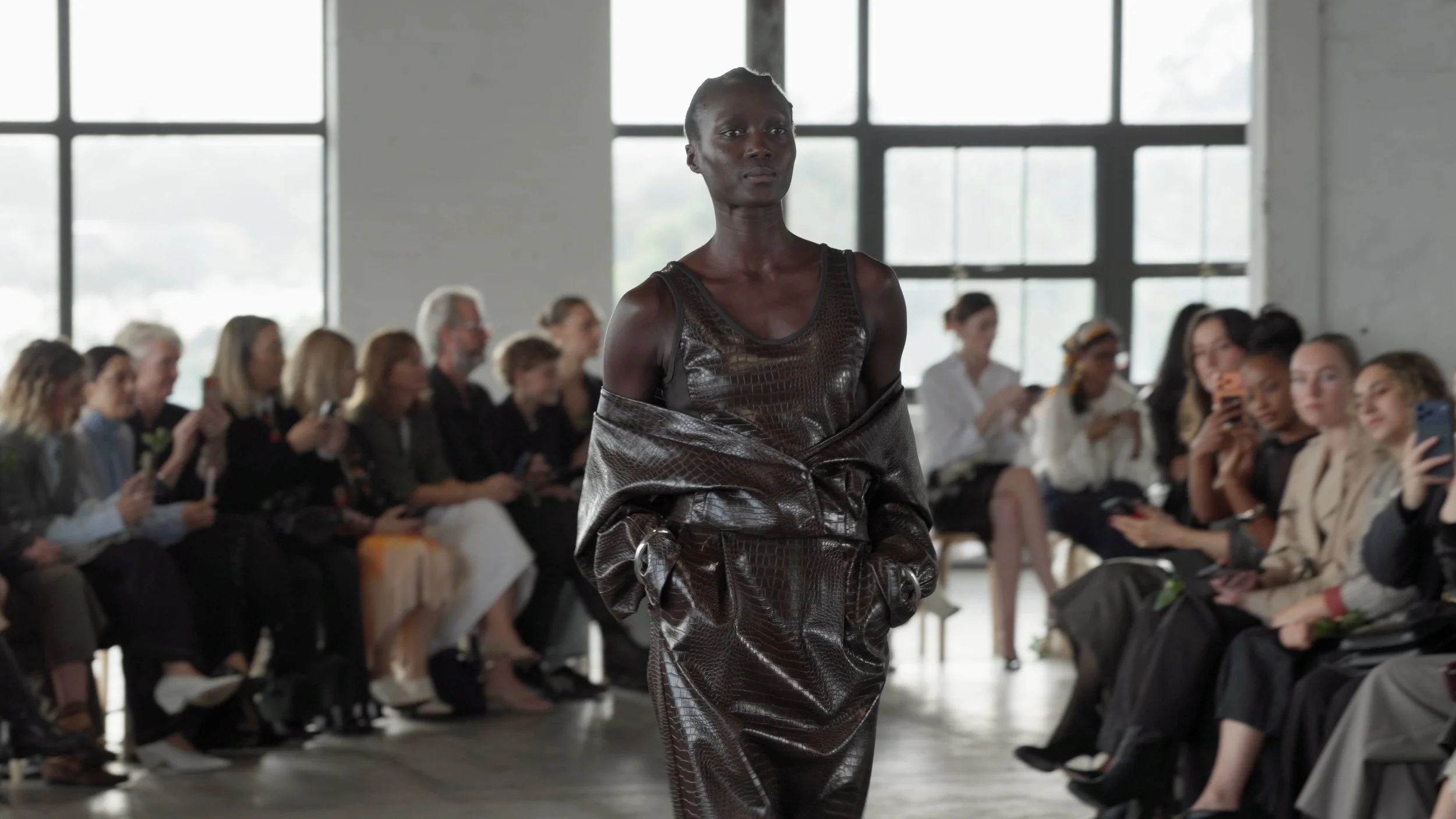 Mid shot of a model in a metallic dark dress walking the runway at Australian Fashion Week.