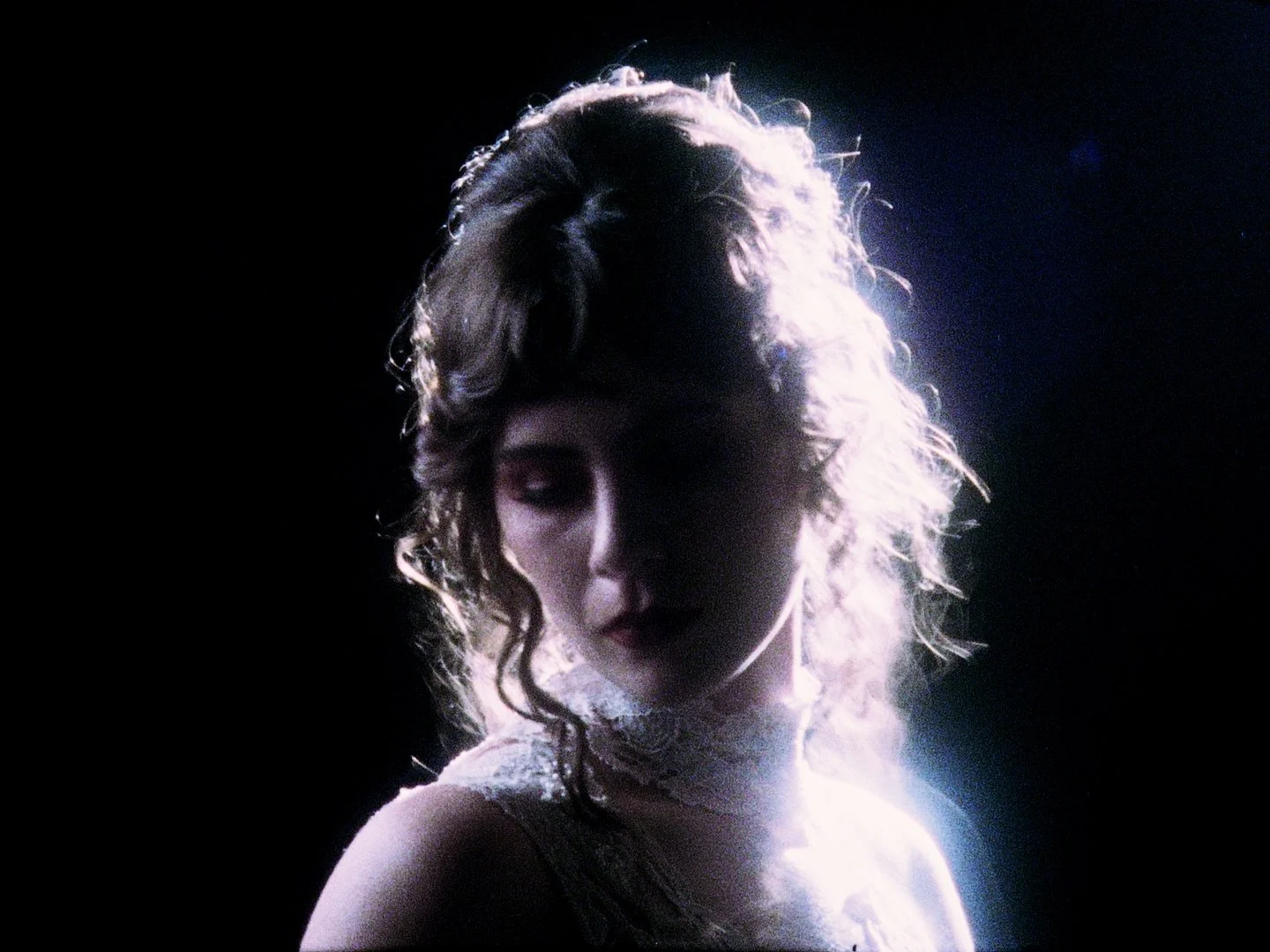 Silhouetted woman looking downward in a dark interior space