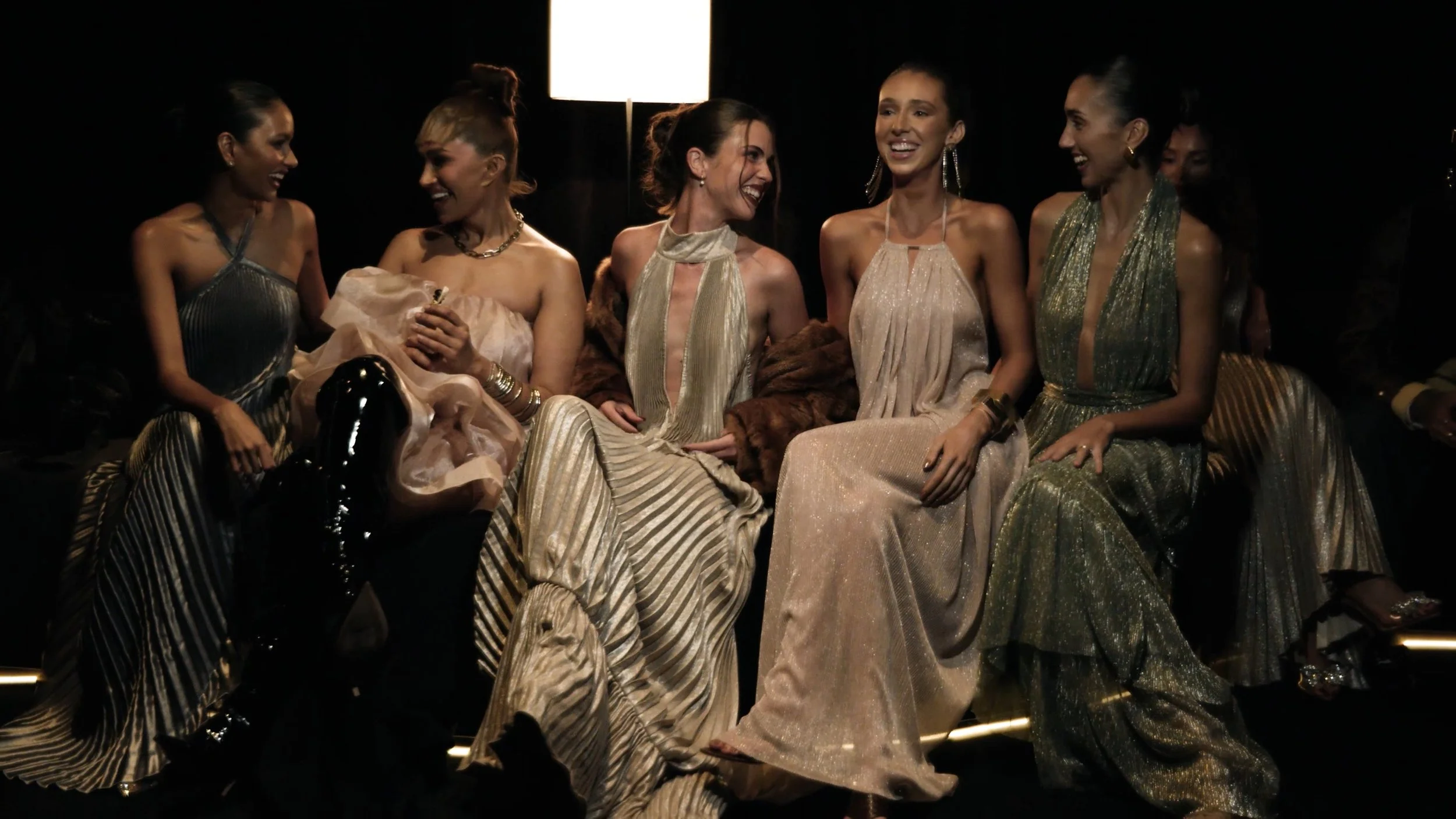 Candid fashion week cinematography of models in designer evening wear seated at AFW Sydney.