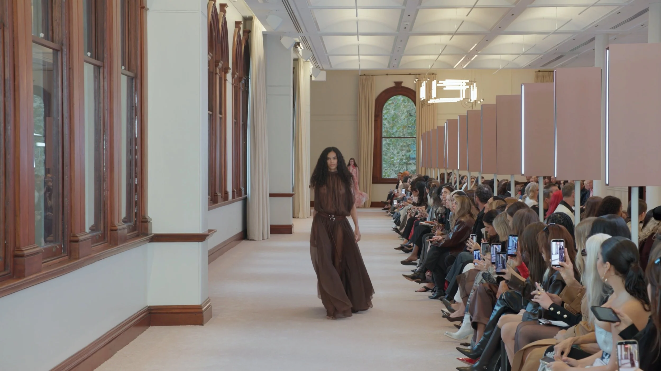 Bright showroom fashion runway photography featuring a model in a flowing brown gown at Australian Fashion Week.