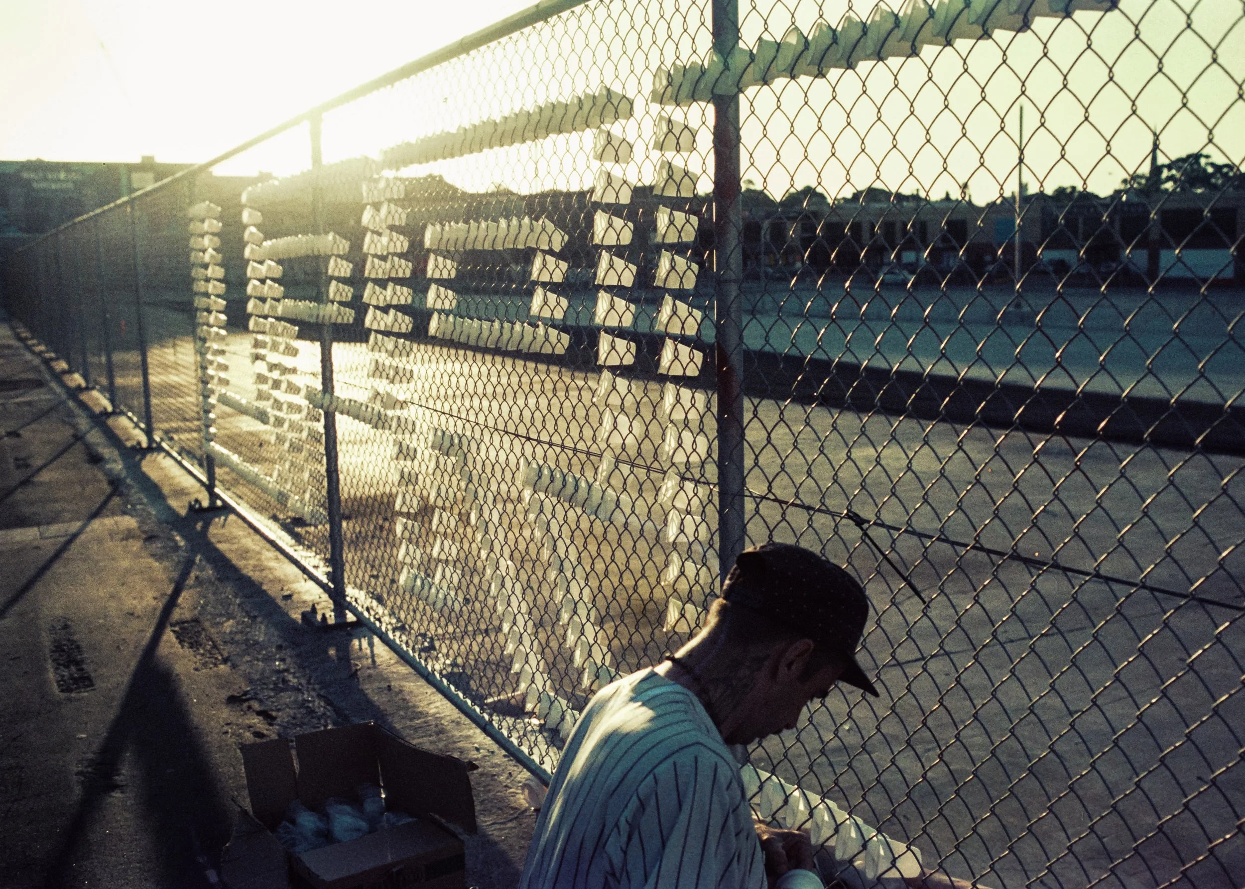 Artist Anyd Uprock placing plastic cups inside a chain link fence creating graffiti