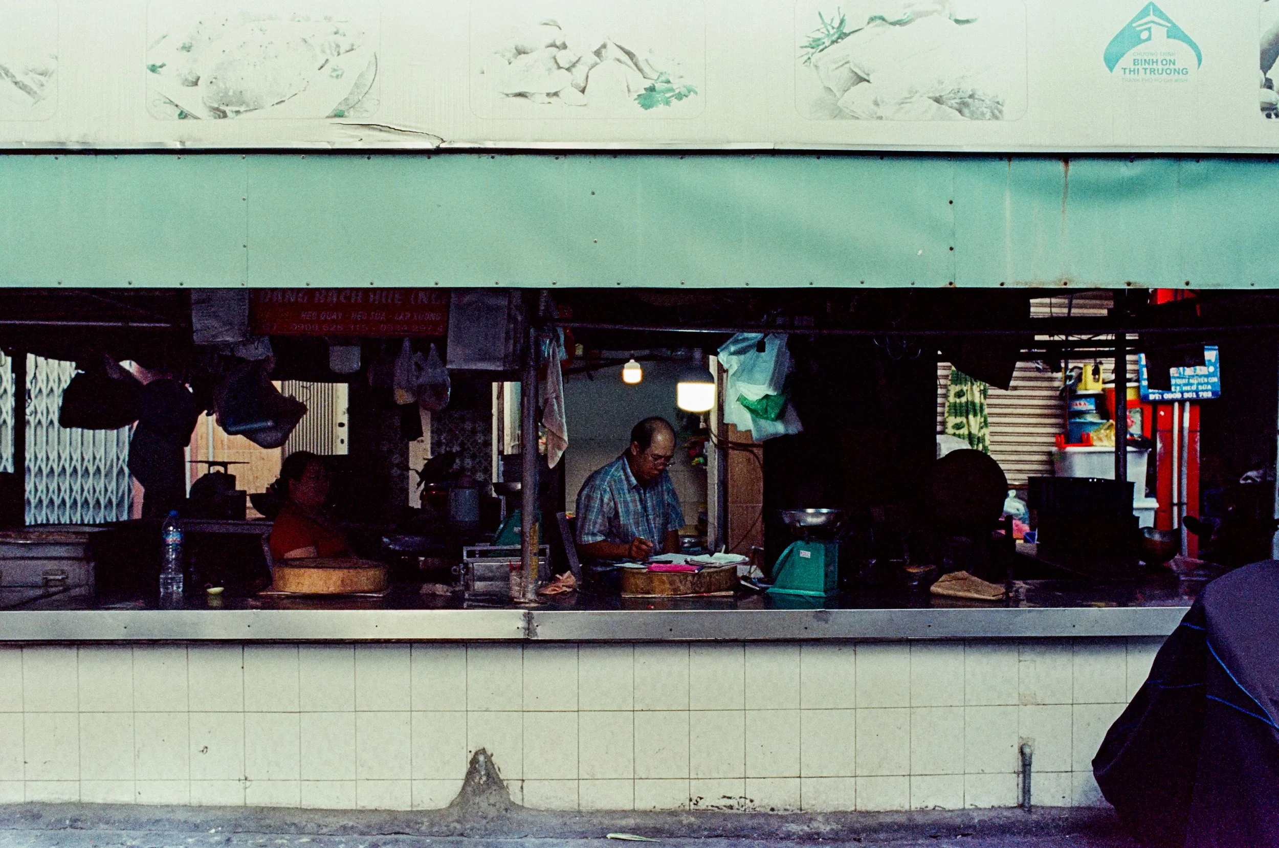 Worker standing among goods at an outdoor market in Vietnam