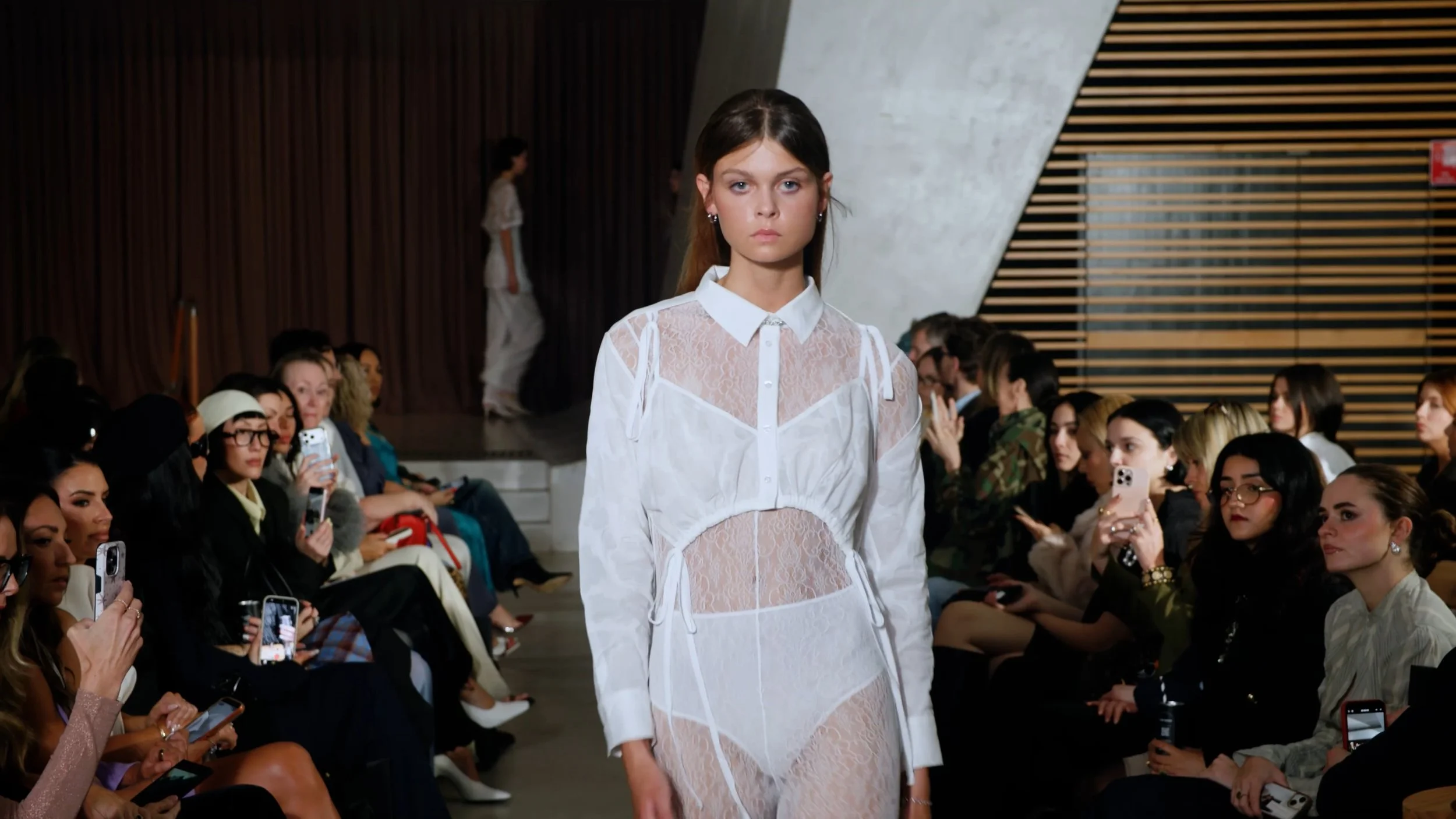 Medium shot of a model walking a modern wood-paneled runway at Australian Fashion Week.