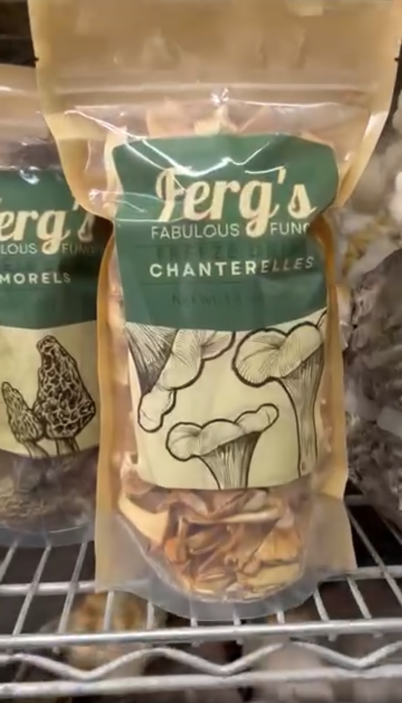 Bag of fresh chanterelle mushrooms on a wire shelf.