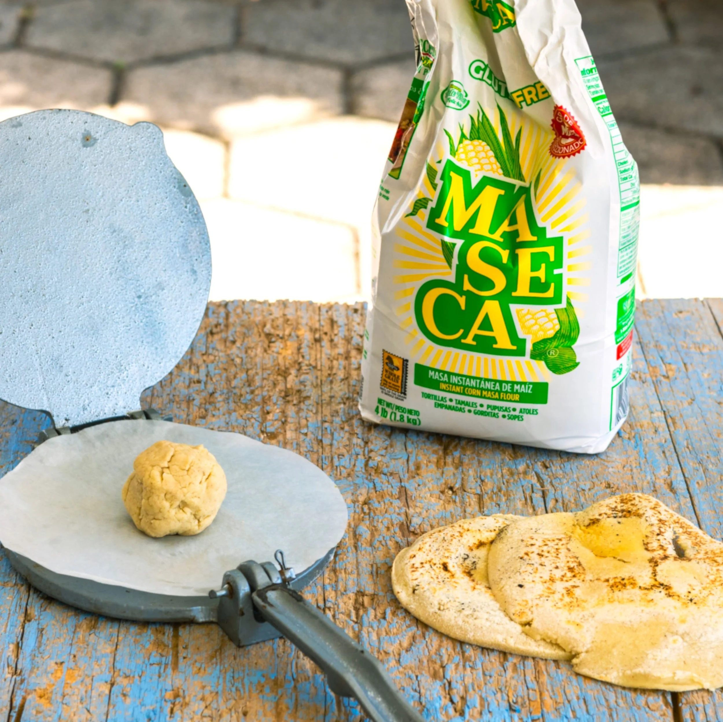a bag of corn tortilla flour with a tortilla press and masa dough