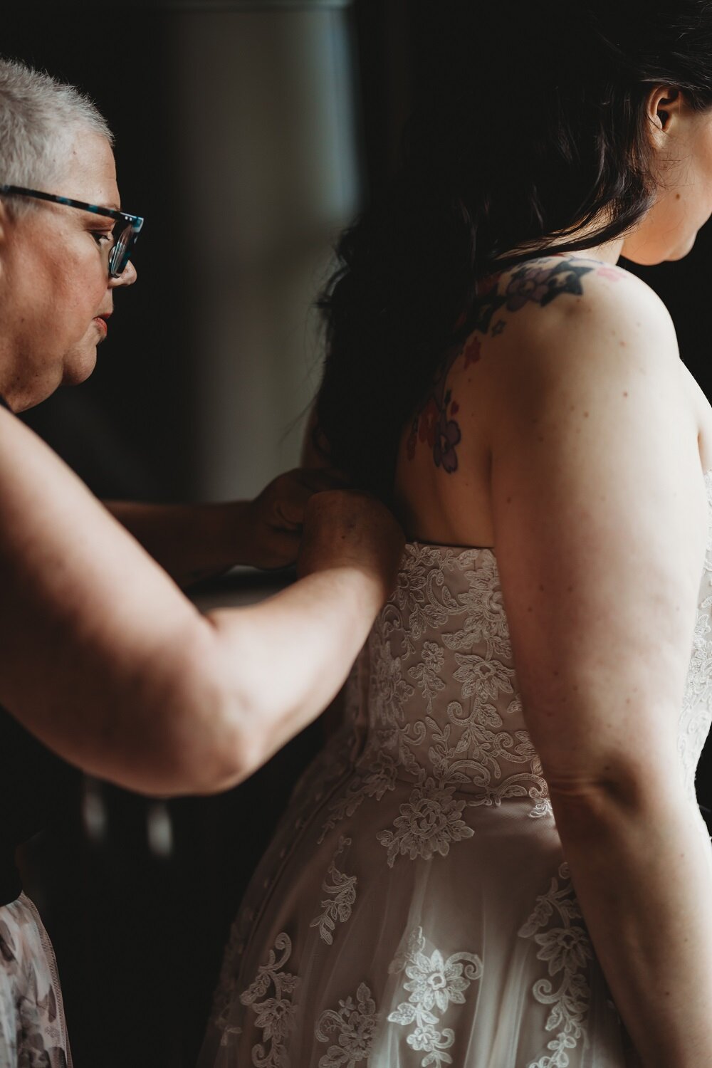 mother of bride helps bride into her wedding dress