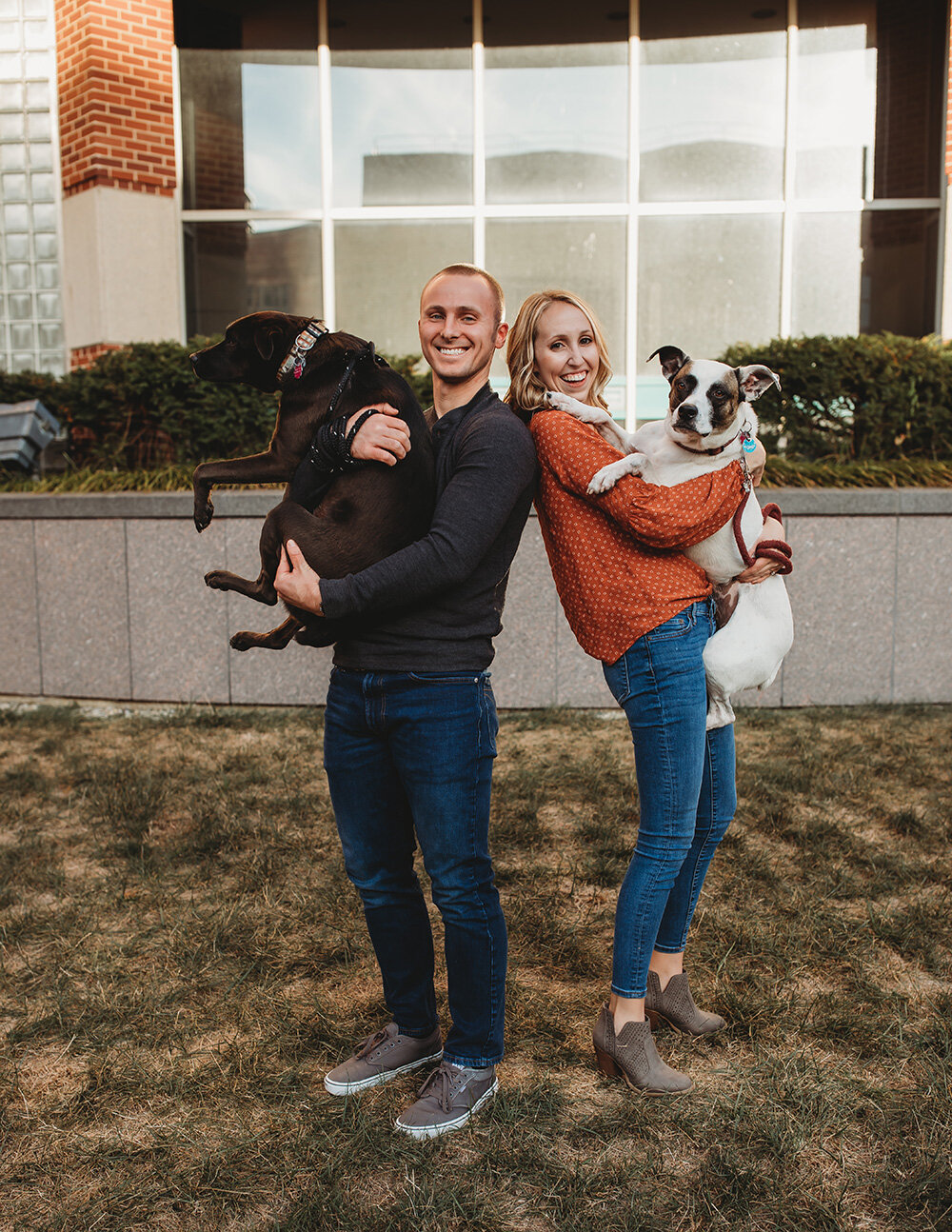 Engaged couple holding their dogs. 