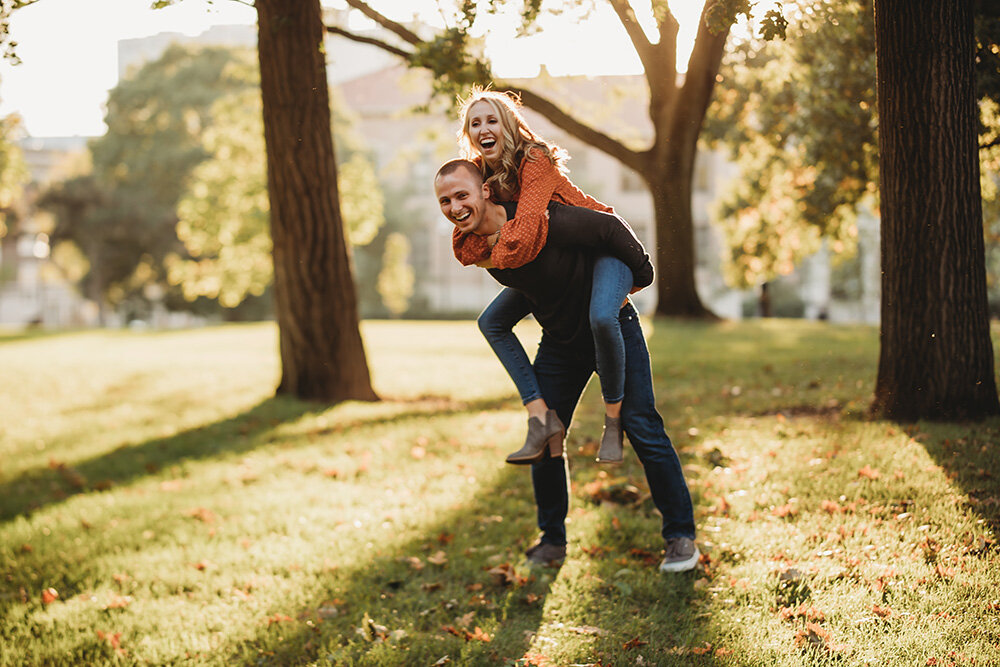 Engaged couple giving each other piggyback rides. 