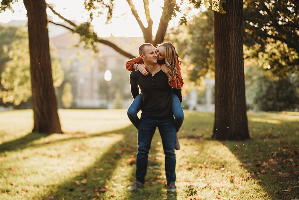 Engaged couple giving each other piggyback rides.