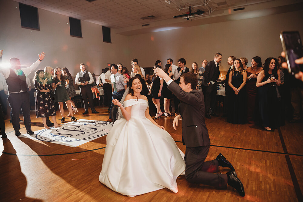 groom getting garter off of bride 