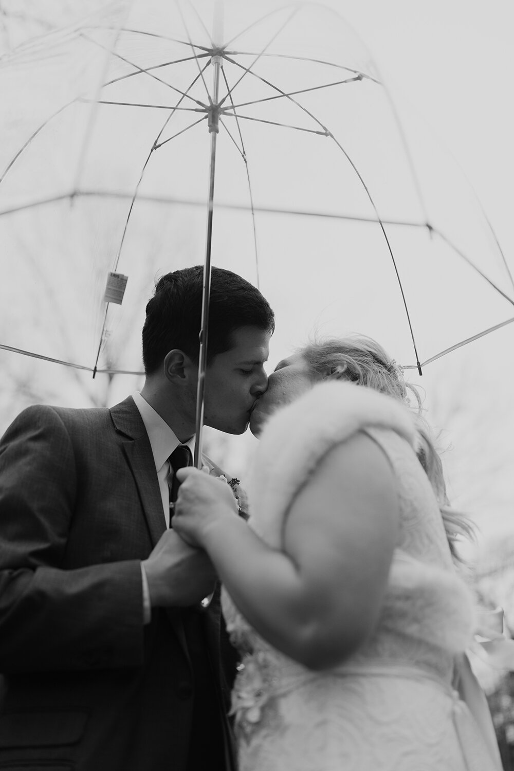 bride and groom sharing a kiss under an umbrella 