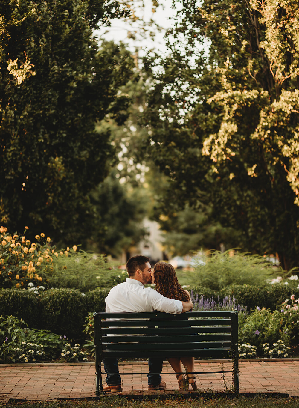 couple kissing on park bench 
