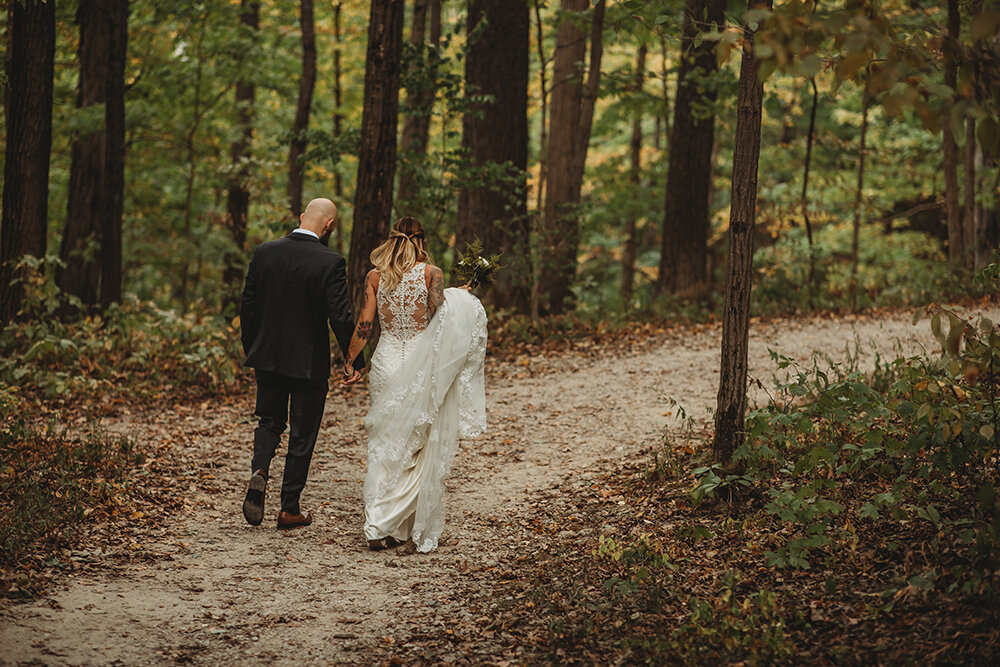 bride and groom walking in the woods 